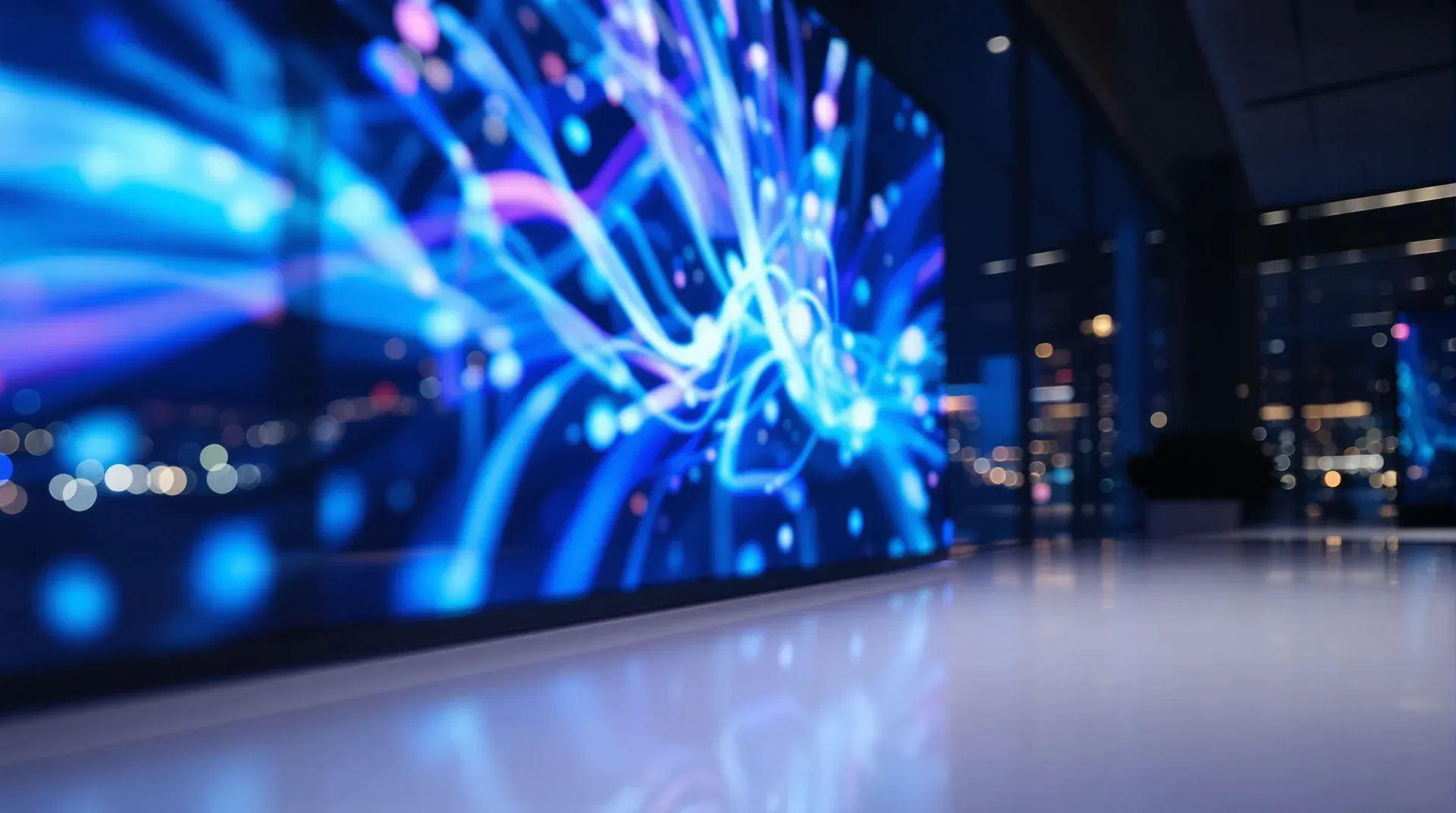 Oficina de noche con una pantalla grande de visualizaciones de datos en azul y violeta.